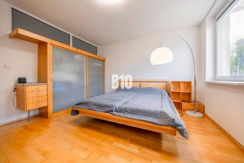 POD HRADOM - ZÁMOCKÁ - 3 IZBOVÝ BYT NA BÝVANIE AJ INVESTÍCIU - Spálňa s posteľou, vstavanou skriňou a podlahou s dreveným dekorom v 3-izbovom byte.