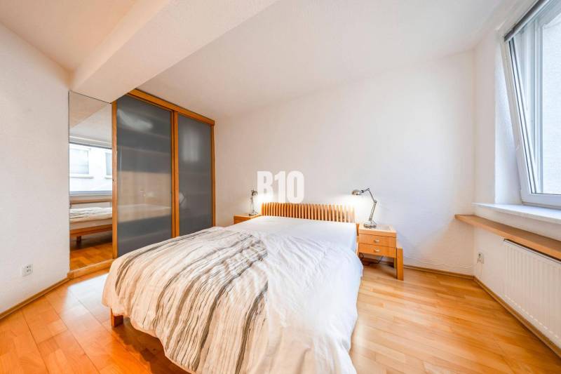 POD HRADOM - ZÁMOCKÁ - 3 IZBOVÝ BYT NA BÝVANIE AJ INVESTÍCIU - Spálňa v 3-izbovom byte s posteľou, skriňou, nočnými stolíkmi a podlahou s dreveným dekorom.