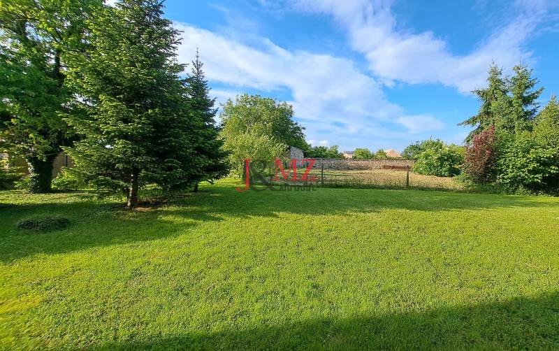 Rodinný dom, garáž a záhrada 1.400 m2, Hronské Kosihy (SM–847) - Záhrada rodinného domu v Hronských Kosihách s udržiavaným trávnikom a stromami.