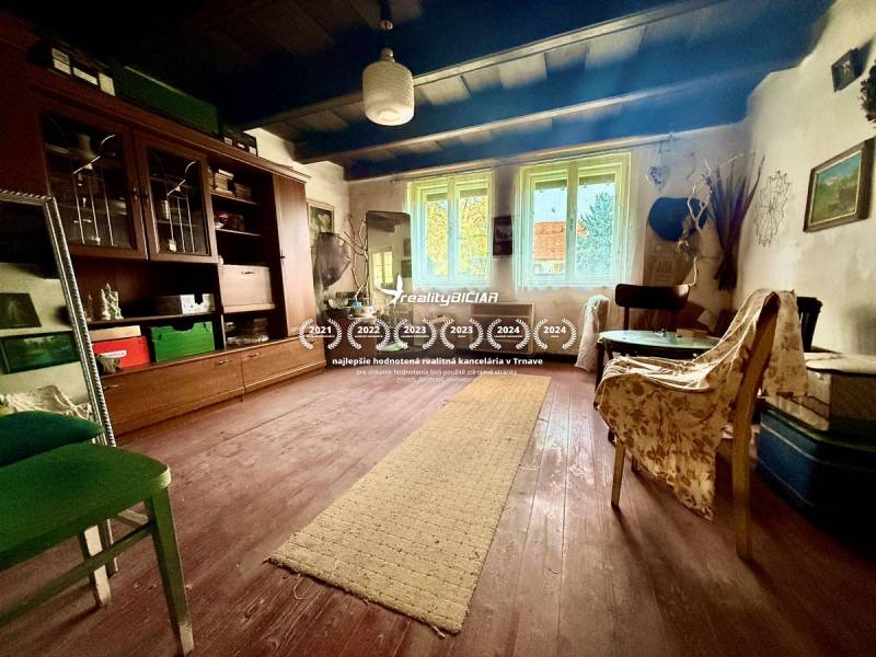 Dom v Budmericiach s možnosťou rekreácie aj trvalého bývania - Obývacia izba v rodinnom dome s podlahou s dreveným dekorom a starožitným nábytkom.