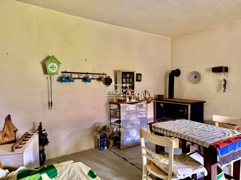 Dom v Budmericiach s možnosťou rekreácie aj trvalého bývania - Jedáleň v rodinnom dome s pecou, stolom a ozdobnými hodinkami na stene.