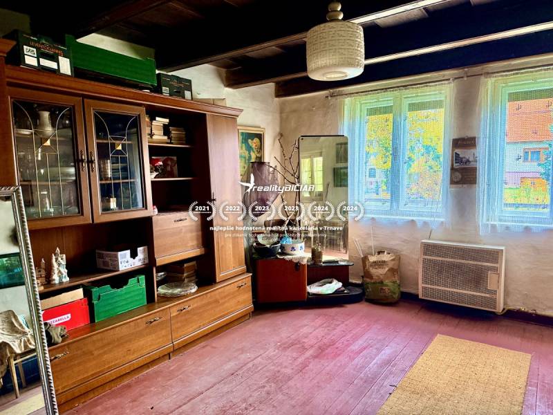 Dom v Budmericiach s možnosťou rekreácie aj trvalého bývania - Izba v rodinnom dome so starým nábytkom a podlahou s dreveným dekorom.