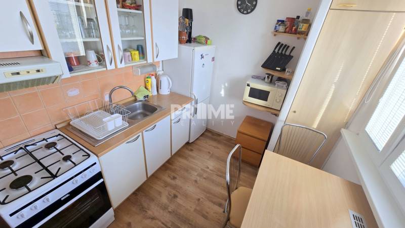 Príjemný 1i byt, zariadený, pivnica, Drobného ul., Dúbravka - Kuchyňa v 1-izbovom byte so sporákom, umývadlom a podlahou s dreveným dekorom.