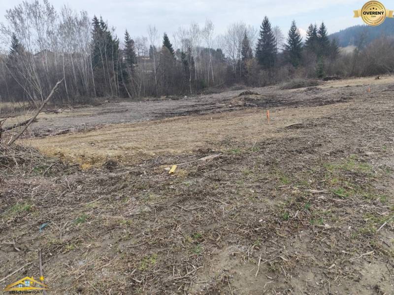 Na predaj: slnečný rovinatý stavebný pozemok – Raková (335-P) - Stavebný pozemok v Rakovej obklopený stromami, pripravený na nové bývanie.