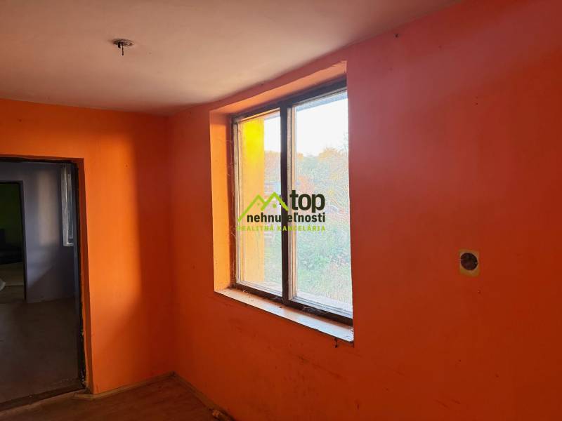 RD TVRDOMESTICE, pozemkom s prístupom z oboch strán - Miestnosť s oranžovými stenami a veľkým oknom, podlaha s dreveným dekorom.