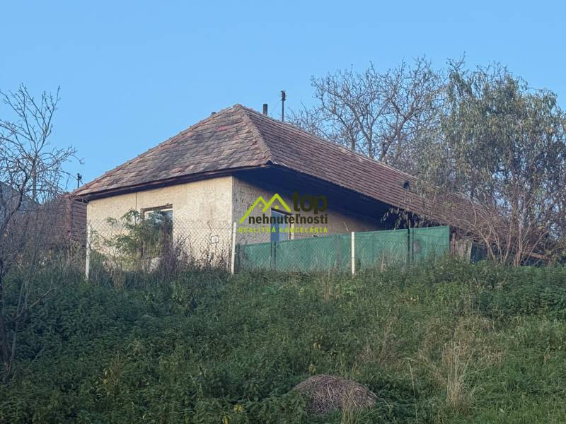 RD TVRDOMESTICE, pozemkom s prístupom z oboch strán - Súčasťou Tvrdomestíc je rodinný dom s drevenou strechou, obklopený zeleňou a plotom.