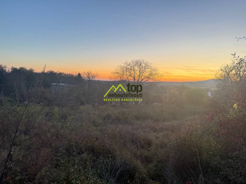 RD TVRDOMESTICE, pozemkom s prístupom z oboch strán - Západ slnka nad pokojným prírodným prostredím v Tvrdošmesticiach, jemne osvetľujúc rodinné domy.