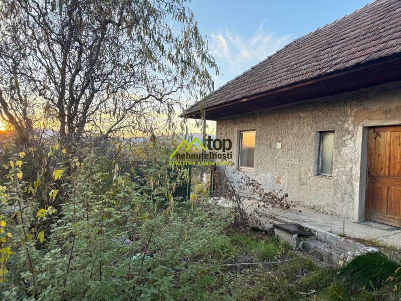 RD TVRDOMESTICE, pozemkom s prístupom z oboch strán - Rodinný dom v Tvrdomesticiach pri západe slnka, v obklopení zelenej vegetácie.