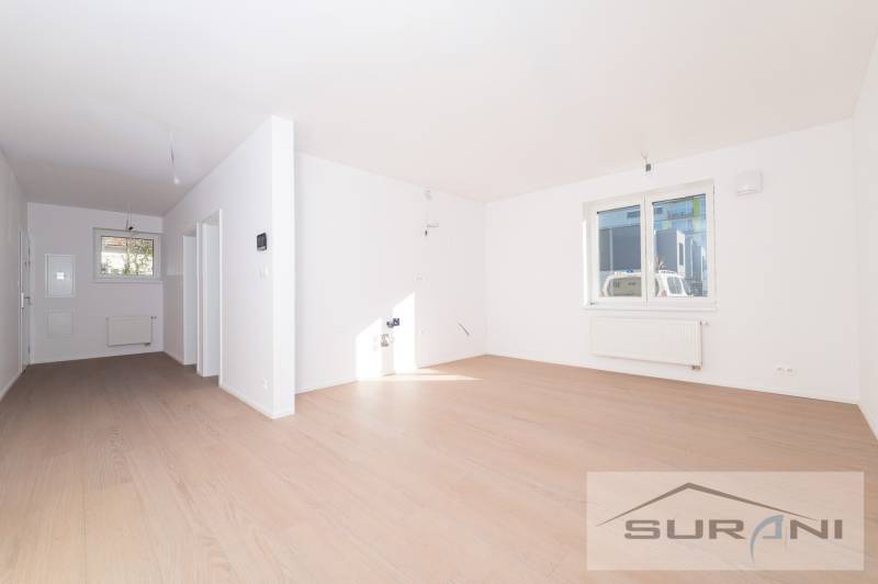 2-izbový byt s predzáhradkou 135 m² a parkovaním v tichej časti BA - Svetlá obývacia izba s oknom a podlahou s dreveným dekorom v 2-izbovom byte.