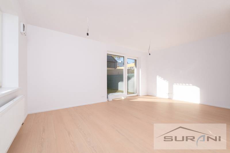 2-izbový byt s predzáhradkou 135 m² a parkovaním v tichej časti BA - Svetlá obývacia izba s podlahou s dreveným dekorom a veľkým oknom v 2-izbovom byte.