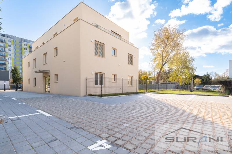 2-izbový byt s predzáhradkou 135 m² a parkovaním v tichej časti BA - Budova na Železničnej ulici v Bratislave - Vrakuni, obklopená dlaždeným priestorom a zeleňou.