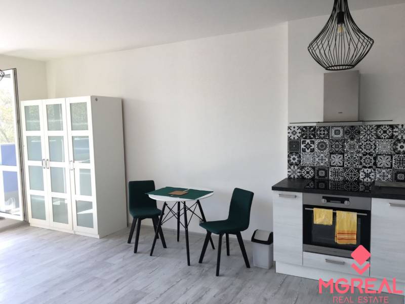 PRENÁJOM 1i byt s Loggiou, Tomášikova ul., Ružinov - Kuchyňa v 1-izbovom byte s podlahou s dreveným dekorom a stolom na jedlo.