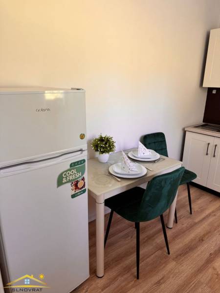 Predaj : 1 izbový byt v meste Čadca časť Žarec  (336-B) - Malá kuchyňa v 1-izbovom byte s chladničkou, stolom a zelenými stoličkami.