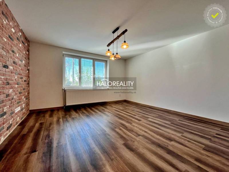 REZERVOVANÉ - Predaj, trojizbový byt Želiezovce, zre... - Izba v 3-izbovom byte s podlahou s dreveným dekorom a tehlovým obkladom na stene.