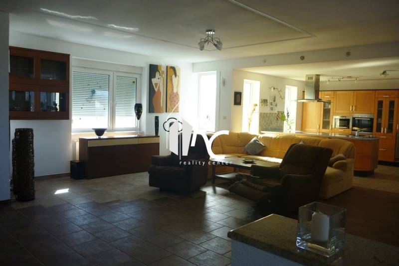 EXKLUZÍVNE, VEĽKÝ RODINNÝ DOM NECPALY - Priestranná obývačka v rodinnom dome s pohodlnou sedačkou a modernou kuchyňou.