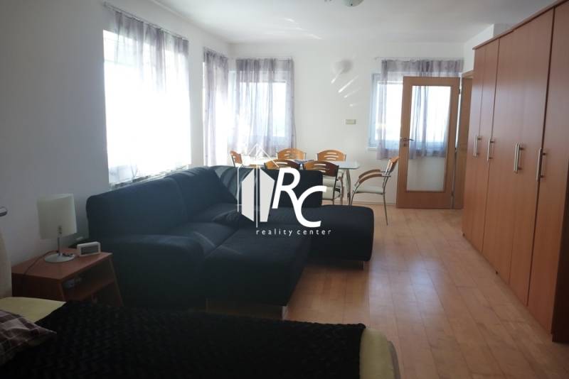 EXKLUZÍVNE, VEĽKÝ RODINNÝ DOM NECPALY - Obývacia izba s čiernou sedačkou, jedálenským stolom a množstvom prirodzeného svetla.