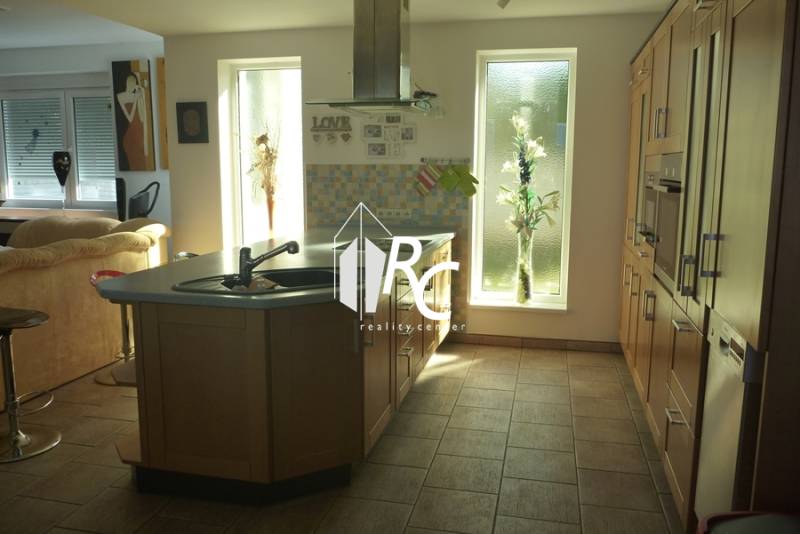 EXKLUZÍVNE, VEĽKÝ RODINNÝ DOM NECPALY - Priestranná kuchyňa v rodinnom dome so svetlými prvkami a ostrovčekom.