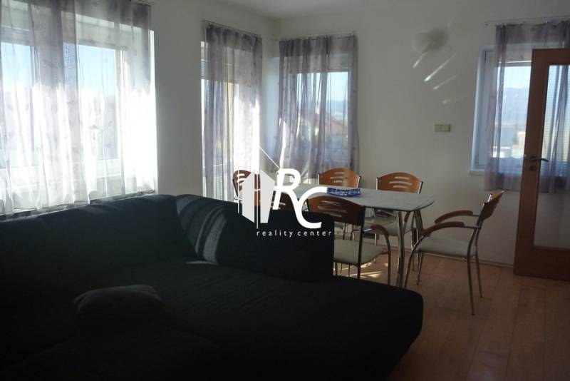 EXKLUZÍVNE, VEĽKÝ RODINNÝ DOM NECPALY - Obývacia izba v rodinnom dome s čiernou sedačkou a jedálenským stolom.