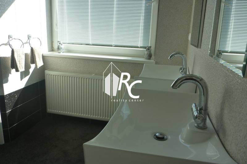 EXKLUZÍVNE, VEĽKÝ RODINNÝ DOM NECPALY - Kúpeľňa rodinného domu s dvomi umývadlami, radiátorom a oknom s žalúziami.