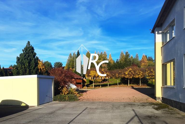 EXKLUZÍVNE, VEĽKÝ RODINNÝ DOM NECPALY - Dvor rodinného domu v Necpaloch s dláždenou plochou a zeleným pozadím.