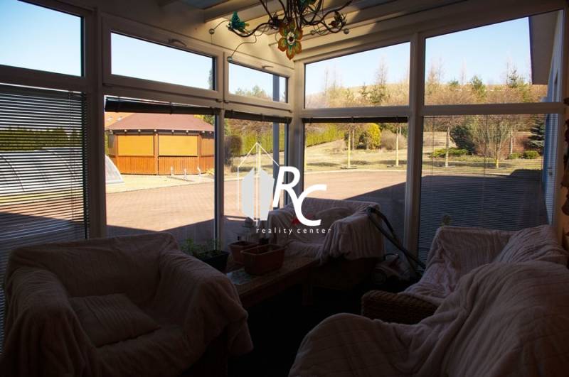 EXKLUZÍVNE, VEĽKÝ RODINNÝ DOM NECPALY - Zimná záhrada rodinného domu s ratanovým nábytkom a výhľadom do dvora.