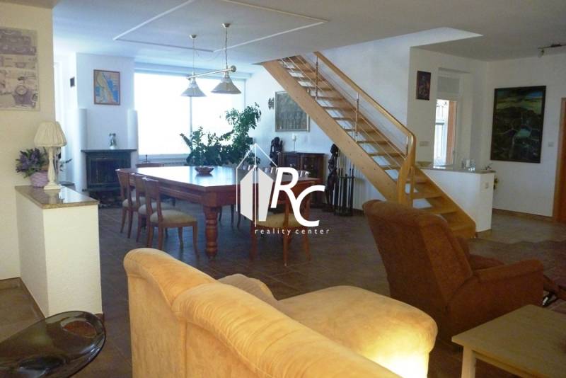 EXKLUZÍVNE, VEĽKÝ RODINNÝ DOM NECPALY - Obývacia izba v rodinnom dome s drevenými schodmi a jedálenským stolom.