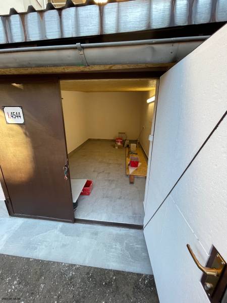 Garáž na Mlynskej ul. na prenájom - Interiér garáže s otvorenými dverami, podlaha s dreveným dekorom, úložný priestor.