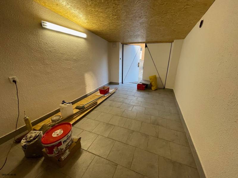 Garáž na Mlynskej ul. na prenájom - Garáže s náradím a osvetlením, podlaha s dreveným dekorom, otvorené dvere na denné svetlo.