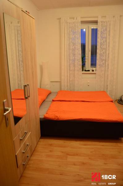 PRIESTRANNÝ 2-IZB BYT V UZAVRETOM AREÁLI, MIEROVÁ KOLÓNIA, NOVÉ MESTO - Spálňa v 2-izbovom byte s posteľou, šatníkom a podlahou s dreveným dekorom.