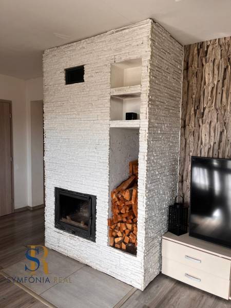 Rodinný dom v obci Dubová s 920m2 rozsiahlym pozemkom  - Interiér rodinného domu s krbom, TV a drevom, podlaha s dreveným dekorom.