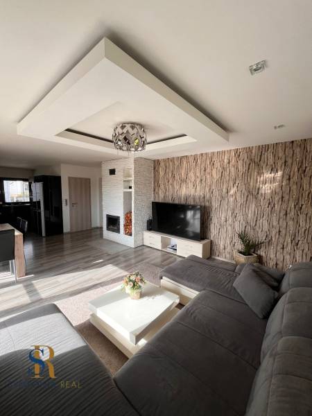 Rodinný dom v obci Dubová s 920m2 rozsiahlym pozemkom  - Obývacia izba v Rodinnom dome s pohovkou, TV a krbom, podlaha s dreveným dekorom.