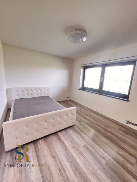 Rodinný dom v obci Dubová s 920m2 rozsiahlym pozemkom  - Spálňa v rodinnom dome s posteľou a podlahou s dreveným dekorom.