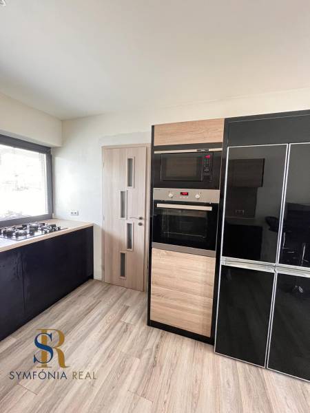 Rodinný dom v obci Dubová s 920m2 rozsiahlym pozemkom  - Kuchyňa v rodinnom dome s plynovým sporákom a spotrebičmi, podlaha s dreveným dekorom.