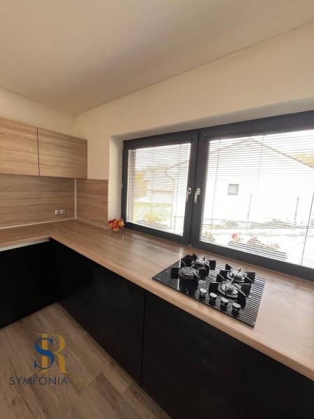 Rodinný dom v obci Dubová s 920m2 rozsiahlym pozemkom  - Kuchyňa s dreveným dekorom a pultom v rodinnom dome, s oknom a plynovým varičom.