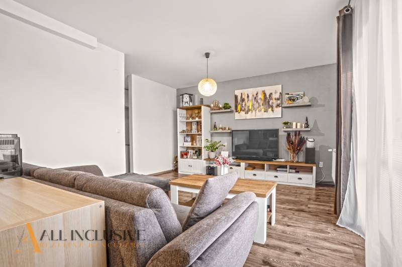 NA PREDAJ 2-IZBOVÝ BYT S 2 BALKÓNMI, DUNAJSKÁ STREDA - Obývacia izba v 2-izbovom byte s podlahou s dreveným dekorom, pohodlným sedením a dekoráciami.