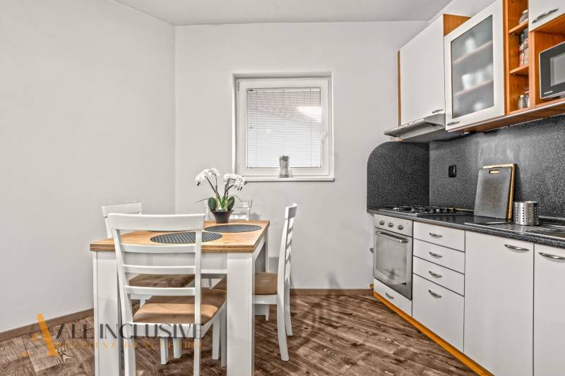 NA PREDAJ 2-IZBOVÝ BYT S 2 BALKÓNMI, DUNAJSKÁ STREDA - Kuchyňa v 2-izbovom byte s jedálenským stolom a podlahou s dreveným dekorom.