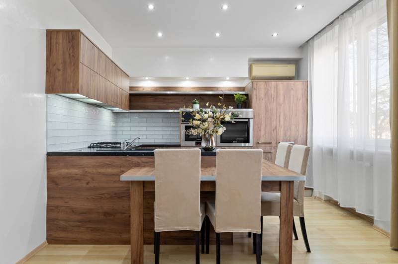 PREDAJ-2 IZBOVÝ BYT-KOMPLETNÁ REKONŠTRUKCIA - RUŽINOV - Kuchyňa v 2-izbovom byte s dreveným dekorom a svetlým nábytkom.