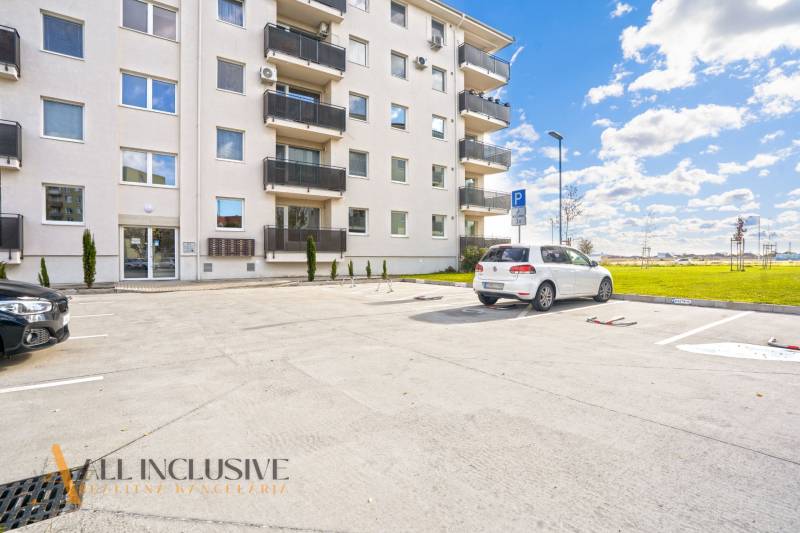 PRENAJATÉ | NA PRENÁJOM 2x 2-IZBOVÉ BYTY S TERASOU,DUNAJSKÁ STREDA - Parkovisko pred bytovým domom na Panónskom háji v Dunajskej Strede, s autami a trávnatou plochou.