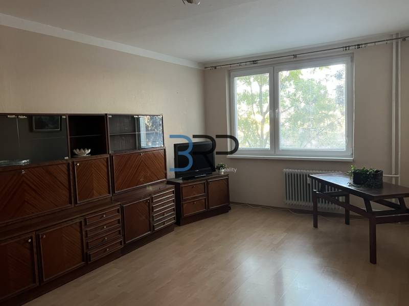 REZERVOVANÝ! Na predaj 2izbový byt v meste Senica - Obývacia izba v 2-izbovom byte s podlahou s dreveným dekorom a nábytkom.