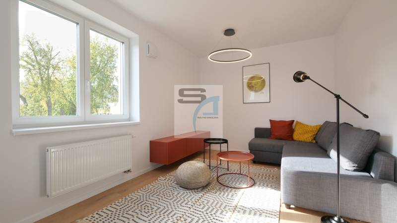 2-izbový byt s terasou 15 m² a parkovaním v tichej časti Bratislavy - Obývacia izba v 2-izbovom byte, sedenie, farebné vankúše, konferenčné stolíky, koberec.