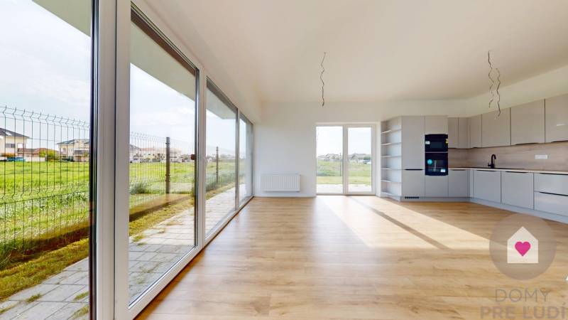 3i. BYT SO ZÁHRADOU +TEP. ČERPADLO, KLIMATIZÁCIA A ŽALÚZIE V CENE - Svetlý priestor v 3-izbovom byte s veľkými oknami a minimalistickou kuchyňou.