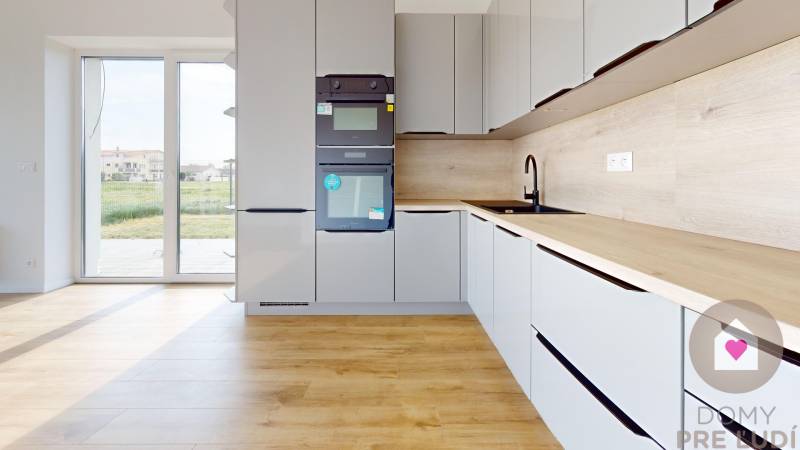 3i. BYT SO ZÁHRADOU +TEP. ČERPADLO, KLIMATIZÁCIA A ŽALÚZIE V CENE - Kuchyňa v 3-izbovom byte so vstavanými spotrebičmi a výhľadom na terasu.