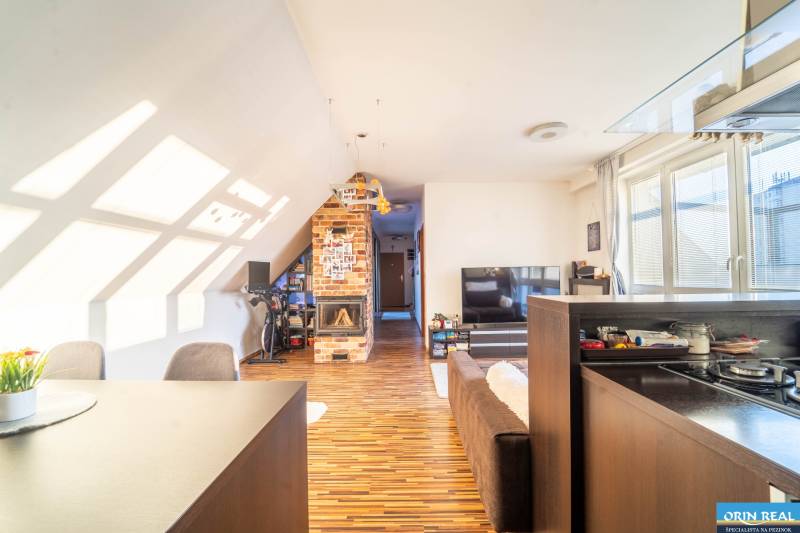 Rezervovaný!!! 2izb + terasa byt Vajanského Modra 93,8m2 - Obývačka v 2-izbovom byte s podlahou s dreveným dekorom a tehlovým krbom.