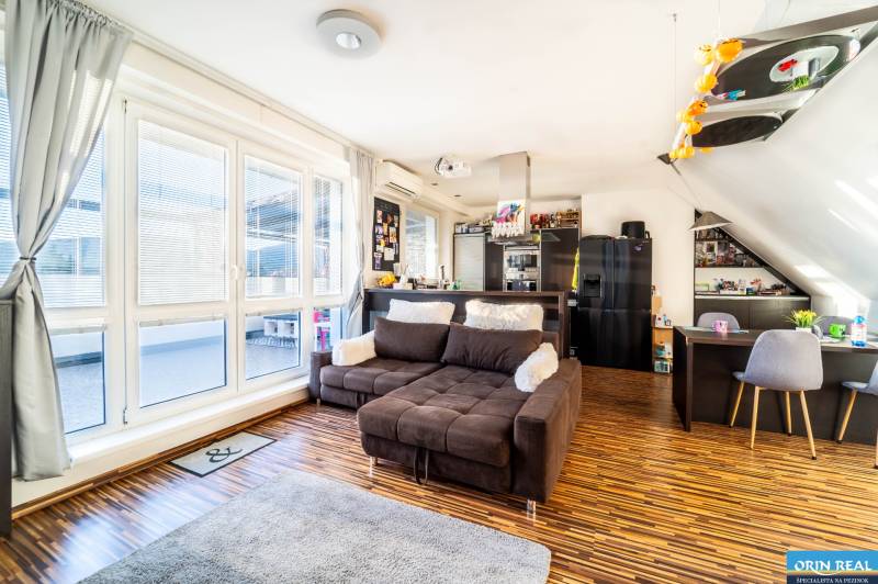 Rezervovaný!!! 2izb + terasa byt Vajanského Modra 93,8m2 - Obývačka s pohodlnou sedačkou, podlahou s dreveným dekorom a veľkými oknami v 2-izbovom byte.