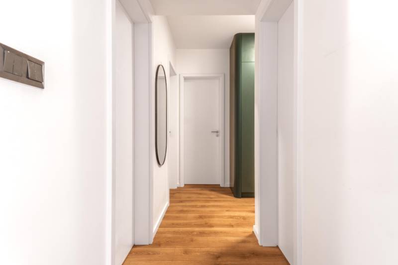 PRENÁJOM 3 izbový byt s predzáhradkou, BORY PROMENÁDA - Úzky interiér s podlahou s dreveným dekorom a jednoduchou bielou stenou v 3-izbovom byte.