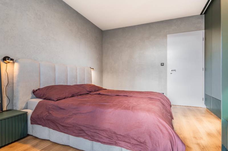 PRENÁJOM 3 izbový byt s predzáhradkou, BORY PROMENÁDA - Spálňa s posteľou v 3-izbovom byte, šedé steny, podlaha s dreveným dekorom.