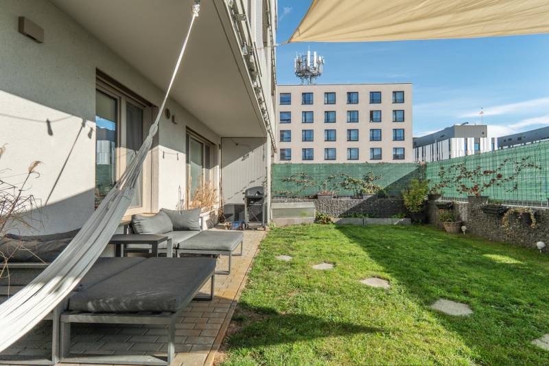 PRENÁJOM 3 izbový byt s predzáhradkou, BORY PROMENÁDA - Záhradná terasa pri 3-izbovom byte v Bratislave - Lamači, Jána Langoša, s trávnikom a závesmi.