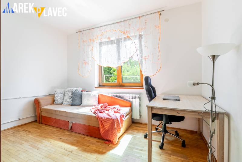 Na predaj: Rodinný dom Slatinské Lazy s očarujúcou atmosférou - Izba v rodinnom dome s posteľou, stolom, stoličkou a podlahou s dreveným dekorom.