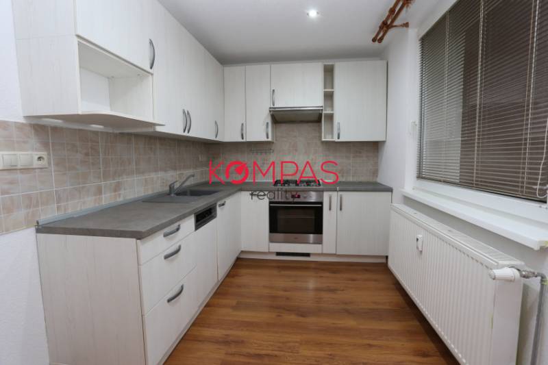 MODERNÝ, KOMPLETNE PREROBENÝ 3-IZB.BYT S LODŽIOU, OČOVÁ - Kuchyňa v 3-izbovom byte s bielymi skrinkami a podlahou s dreveným dekorom.