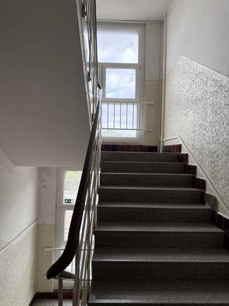 Novinka: Priestranný svetlý byt s balkónmi pri Kuchajde. Vajnorská - Schodisko s kovovým zábradlím a veľkým oknom v bytovom dome.